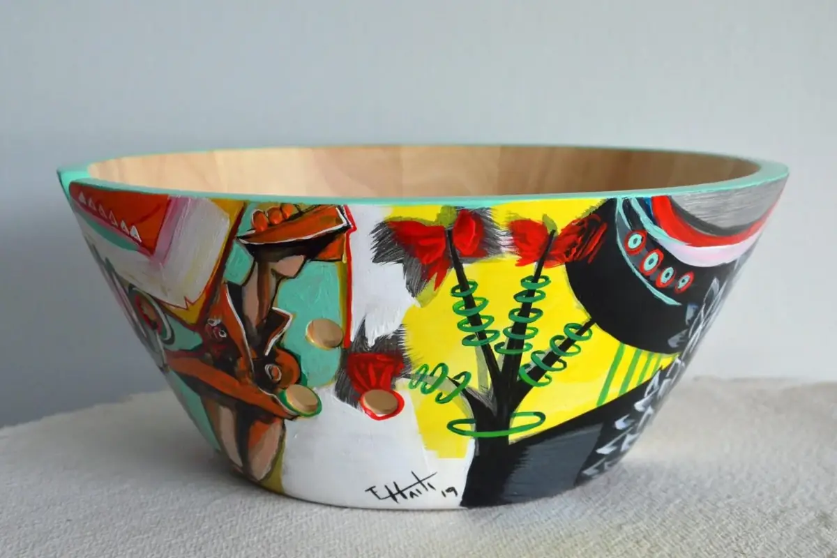 Painted bowl with a tree, fruits and figures in red, yellow and black, signed by the artist.