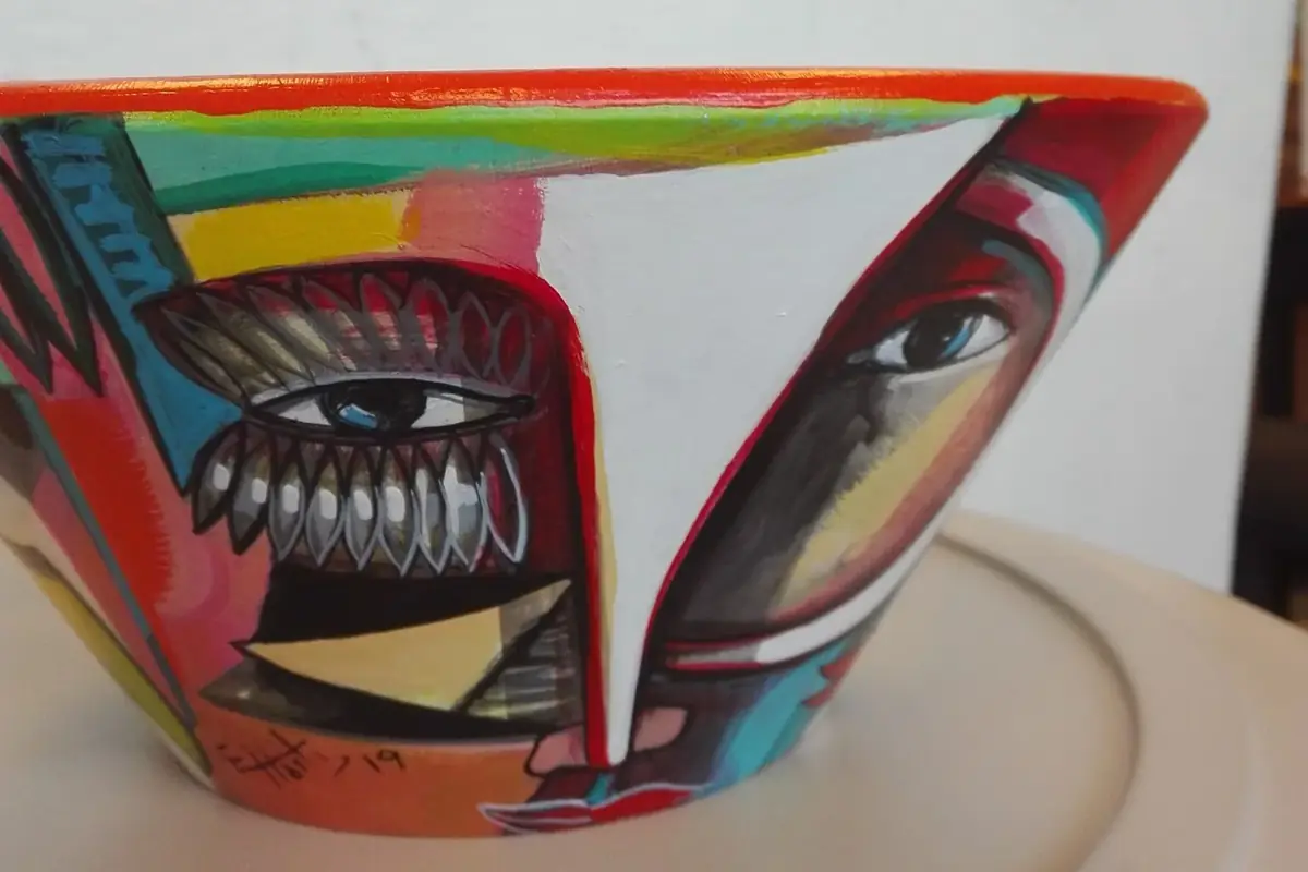 Painted bowl with large eyes and a face in red, turquoise and black.