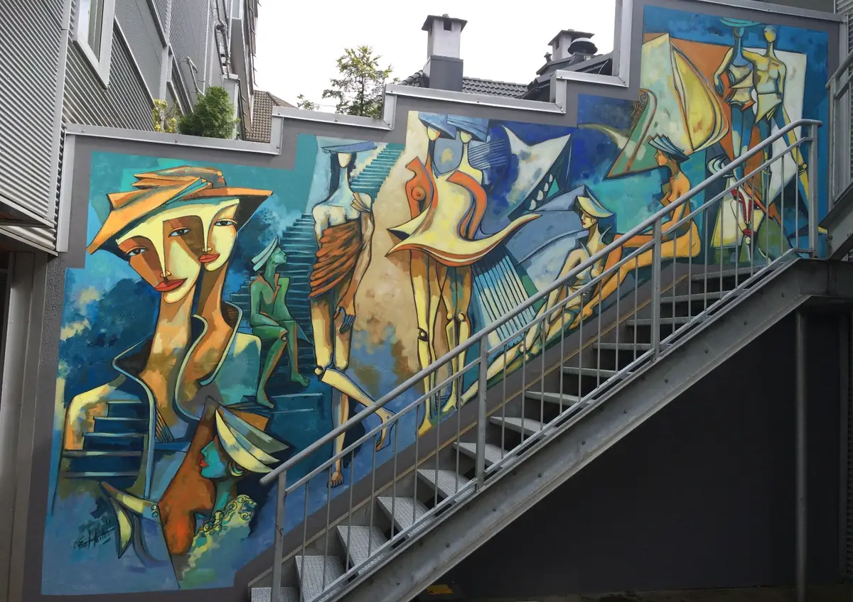 Mural along an outdoor staircase: large figures in blues and ochres.